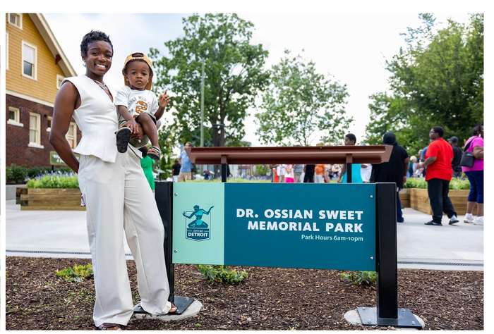 A mother and child at the Dr. Ossian Sweet Memorial Park sign.