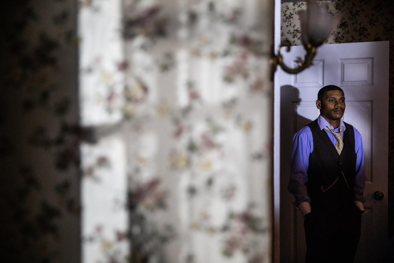 Dr. Ossian Sweet standing in the doorway of his home, lit by a single lamp.