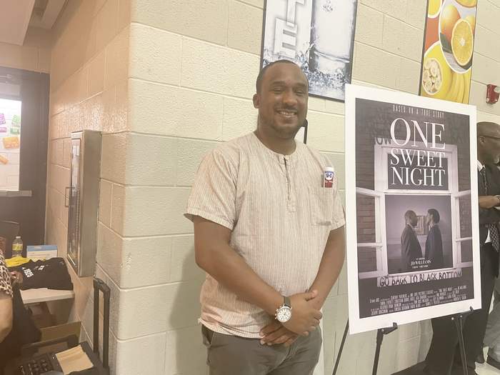 Andrew Colom beside the One Sweet Night poster at a screening.